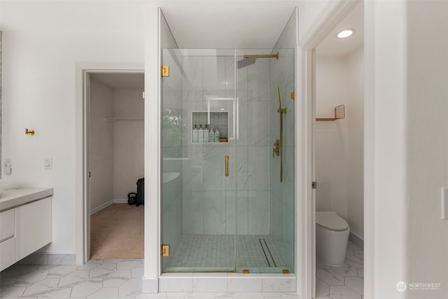 bathroom featuring a shower with shower door, vanity, and toilet