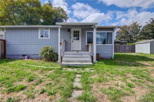 view of front of house featuring a storage unit and a front yard