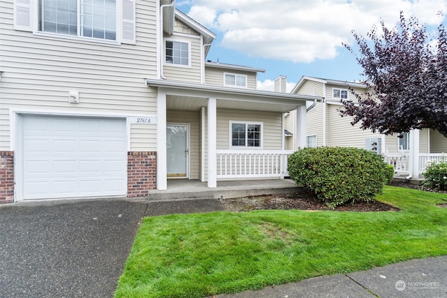 view of front of home with a porch, a front lawn, and a garage