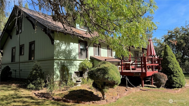 back of property featuring a wooden deck and a yard