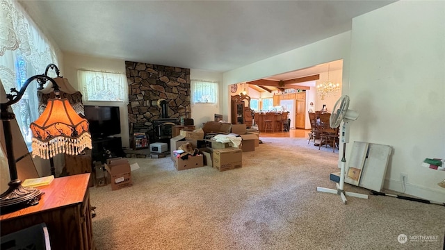 carpeted living room featuring a notable chandelier and a wood stove