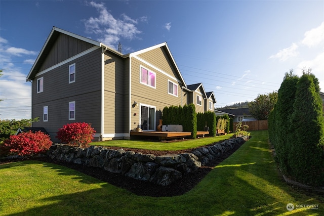 rear view of house featuring a deck and a lawn