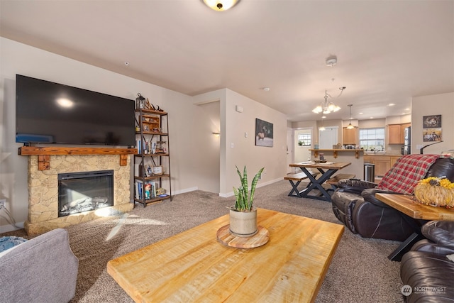 carpeted living room with a stone fireplace and a chandelier