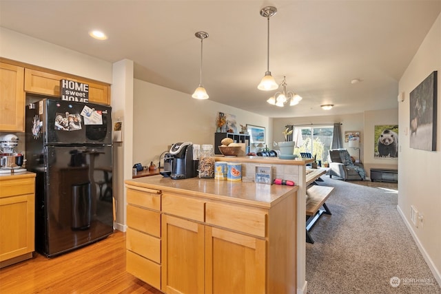 kitchen with a chandelier, light wood-type flooring, pendant lighting, light brown cabinets, and black refrigerator