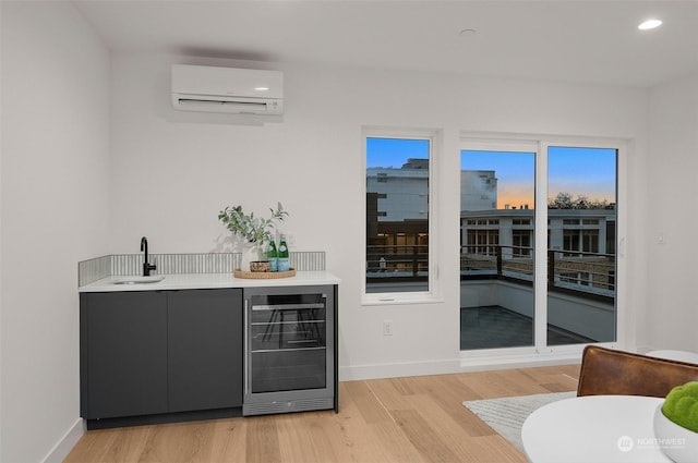 bar featuring light wood-type flooring, sink, beverage cooler, and a wall unit AC