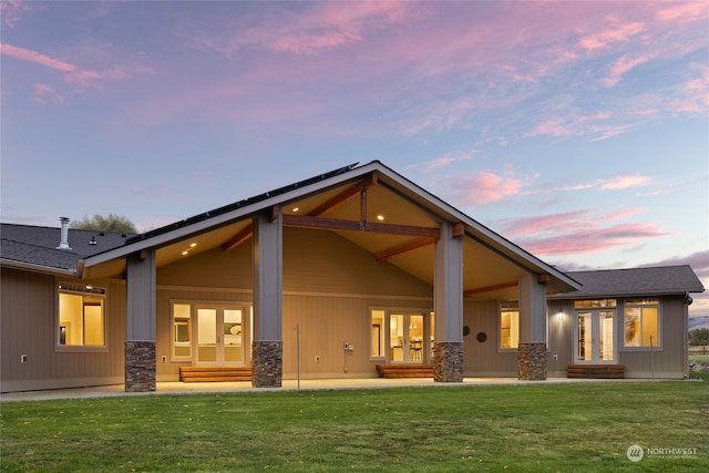 back house at dusk with a lawn