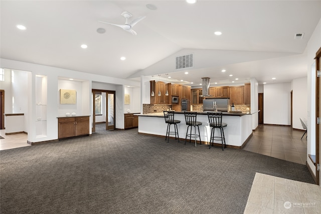 kitchen featuring vaulted ceiling, island range hood, a breakfast bar area, dark colored carpet, and ceiling fan