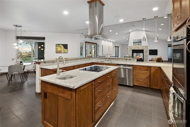 kitchen with appliances with stainless steel finishes, a multi sided fireplace, island range hood, pendant lighting, and sink