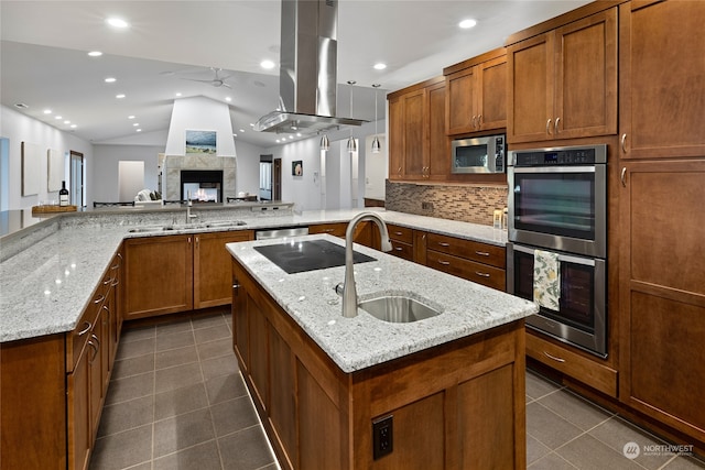 kitchen featuring sink, lofted ceiling, island exhaust hood, stainless steel appliances, and a center island with sink