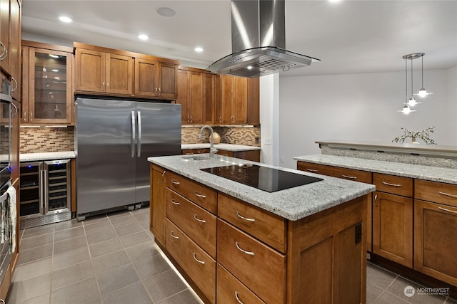 kitchen with island exhaust hood, decorative light fixtures, a kitchen island with sink, and stainless steel fridge