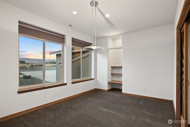 spare room with dark carpet and a water view