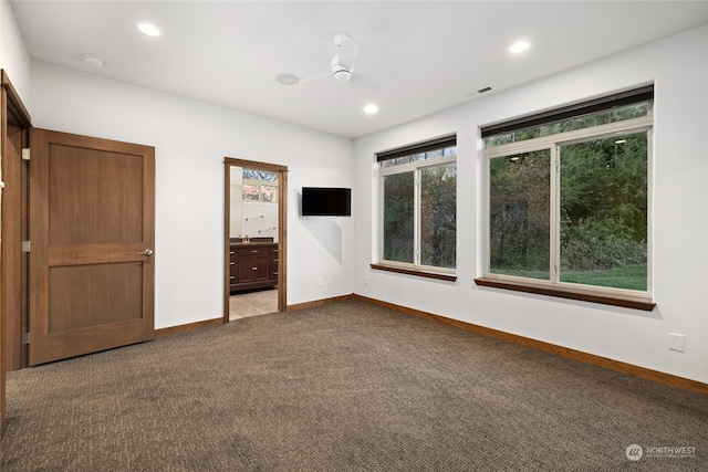 unfurnished bedroom with ceiling fan, light colored carpet, and connected bathroom