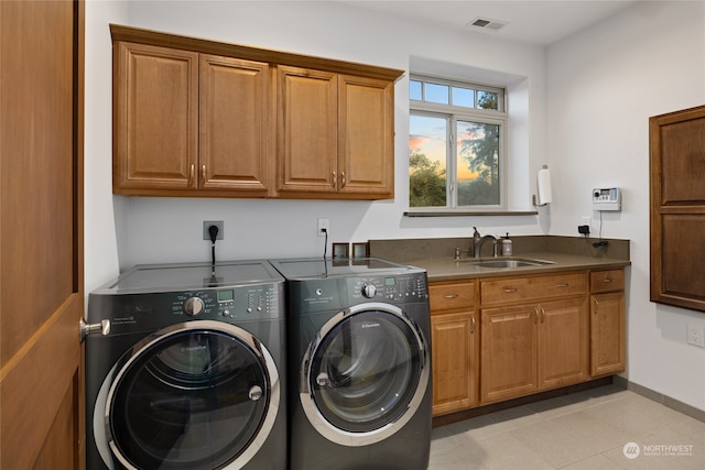 laundry area featuring sink, washer and dryer, and cabinets