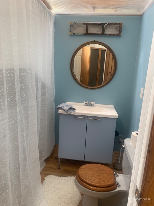 bathroom with hardwood / wood-style floors, vanity, and toilet