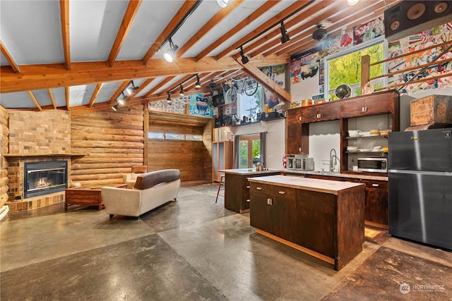 kitchen featuring a center island, stainless steel appliances, vaulted ceiling with beams, a fireplace, and dark brown cabinets