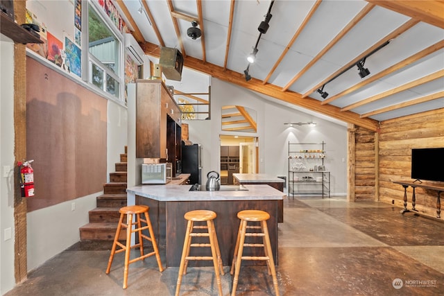 kitchen with lofted ceiling with beams, stainless steel refrigerator, kitchen peninsula, and a breakfast bar