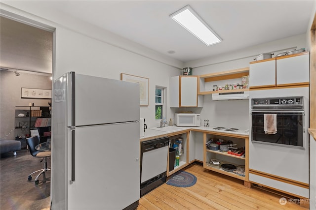 kitchen with white cabinets, light wood-type flooring, white appliances, and sink