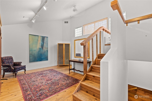 interior space with wood-type flooring, rail lighting, and high vaulted ceiling