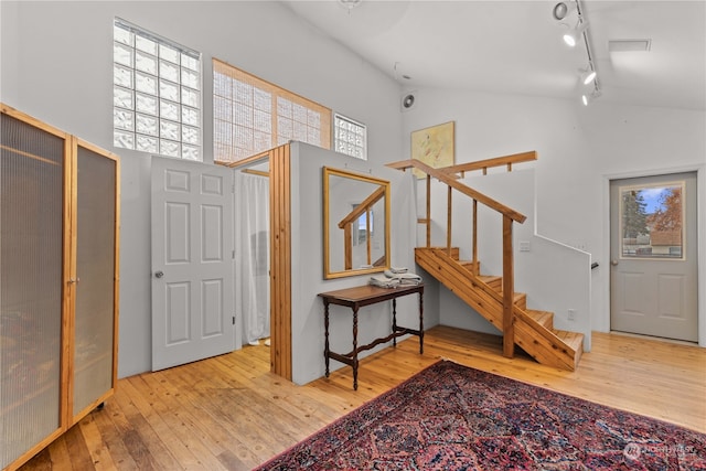 foyer with high vaulted ceiling, rail lighting, a wealth of natural light, and light hardwood / wood-style flooring