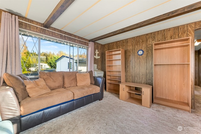 carpeted living room with beamed ceiling and wooden walls