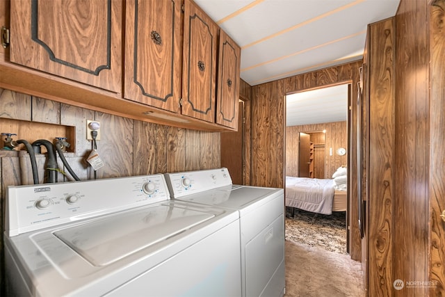 laundry room with washer and dryer, wood walls, and cabinets