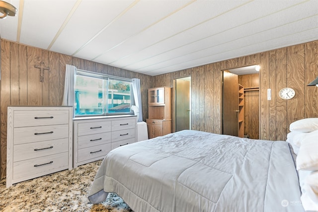 bedroom with a closet, wood walls, carpet, and a walk in closet