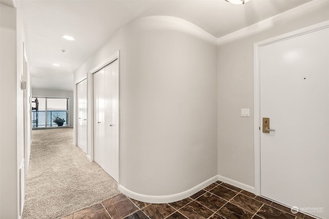 hall with dark colored carpet