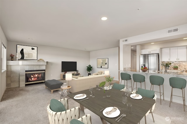 dining area with light colored carpet and a tile fireplace