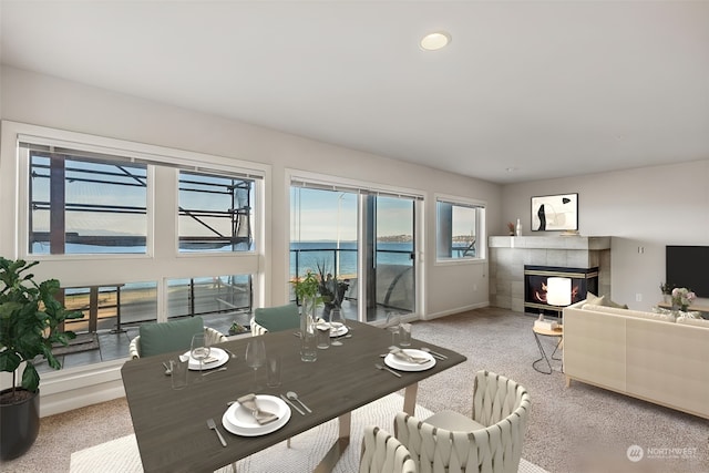 dining space featuring a tiled fireplace, carpet flooring, and a healthy amount of sunlight