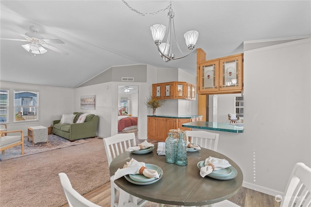 dining space featuring ceiling fan with notable chandelier, lofted ceiling, and light hardwood / wood-style floors