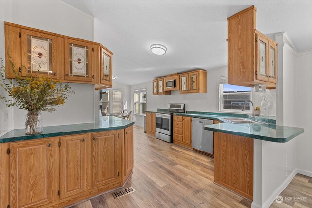 kitchen featuring sink, kitchen peninsula, light hardwood / wood-style flooring, appliances with stainless steel finishes, and crown molding