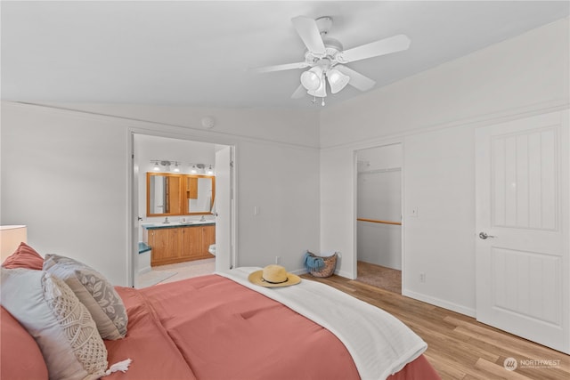 bedroom with light wood-type flooring, a closet, lofted ceiling, ensuite bathroom, and ceiling fan