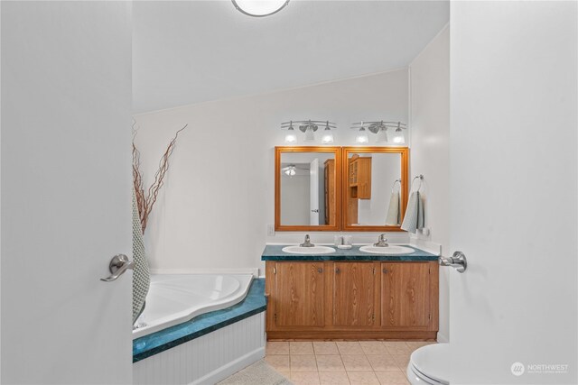 bathroom with vanity, lofted ceiling, a bathing tub, tile patterned floors, and toilet