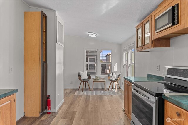 kitchen featuring lofted ceiling, stainless steel electric range, light hardwood / wood-style flooring, crown molding, and black microwave