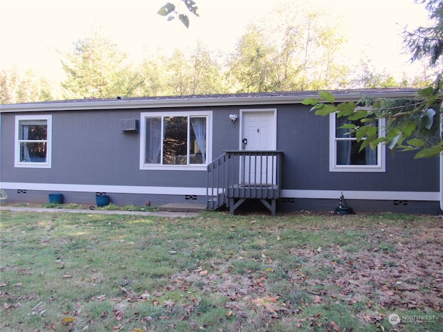 view of front of home featuring a front lawn and a wall mounted AC