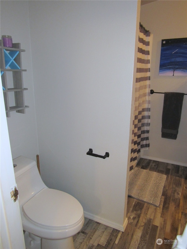 bathroom with hardwood / wood-style floors, toilet, and curtained shower