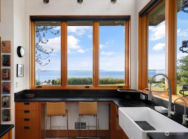 kitchen with visible vents, a sink, a water view, built in desk, and dark countertops