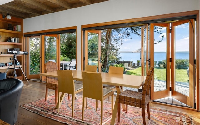 sunroom featuring beamed ceiling and a water view