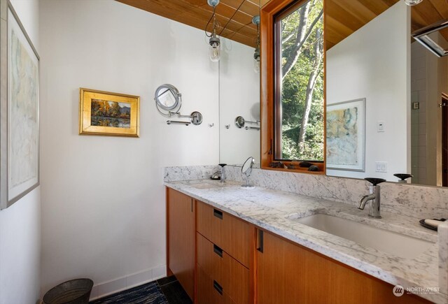 full bathroom featuring double vanity, wooden ceiling, baseboards, and a sink