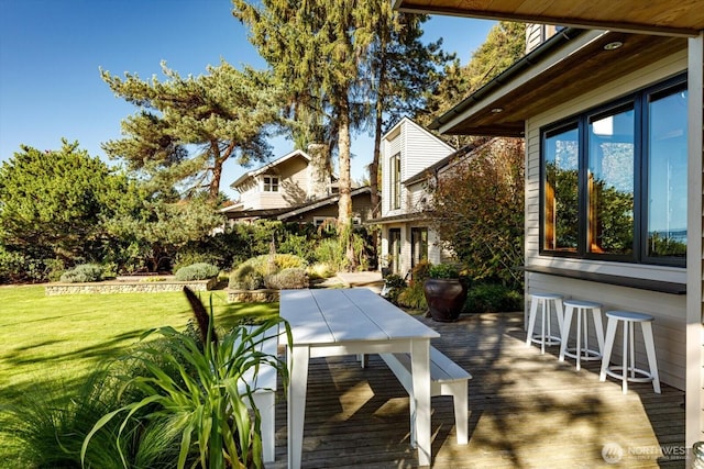 wooden deck featuring outdoor dining space and a lawn