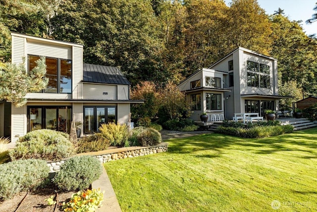 back of house with a yard, a balcony, metal roof, and a standing seam roof