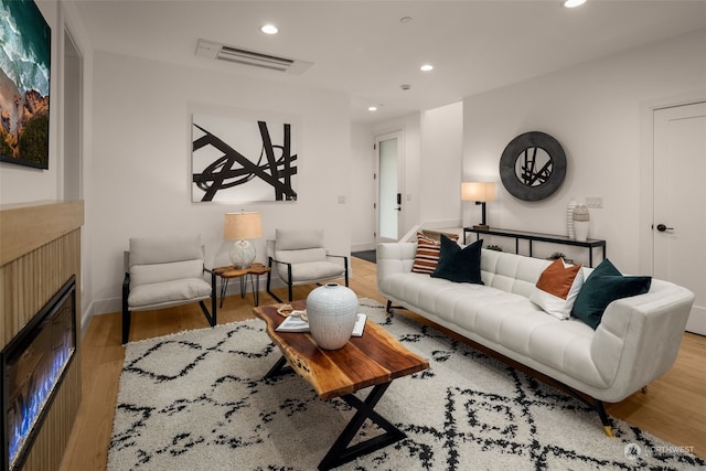 living room with a tiled fireplace and light hardwood / wood-style flooring