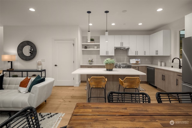 kitchen featuring a kitchen breakfast bar, dishwasher, range, a center island, and hanging light fixtures