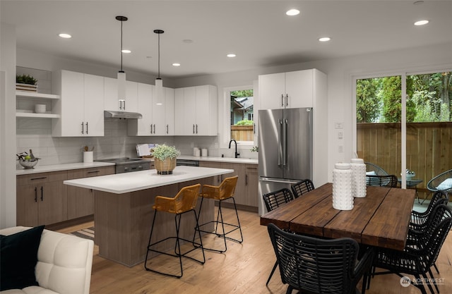 kitchen with a center island, high end fridge, white cabinetry, and pendant lighting