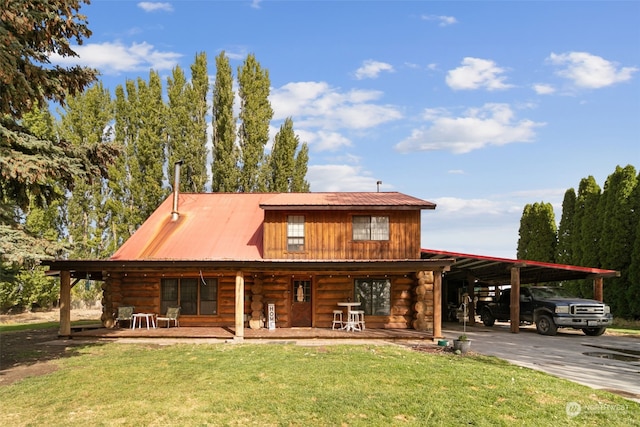 cabin featuring a front yard, covered porch, and a carport