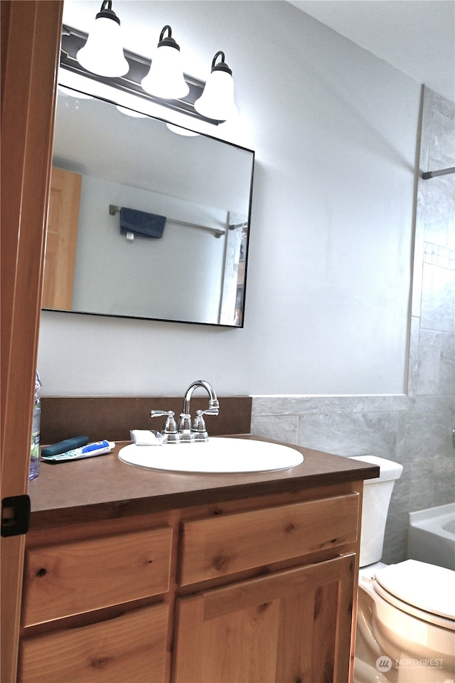 bathroom with vanity, toilet, and tile walls