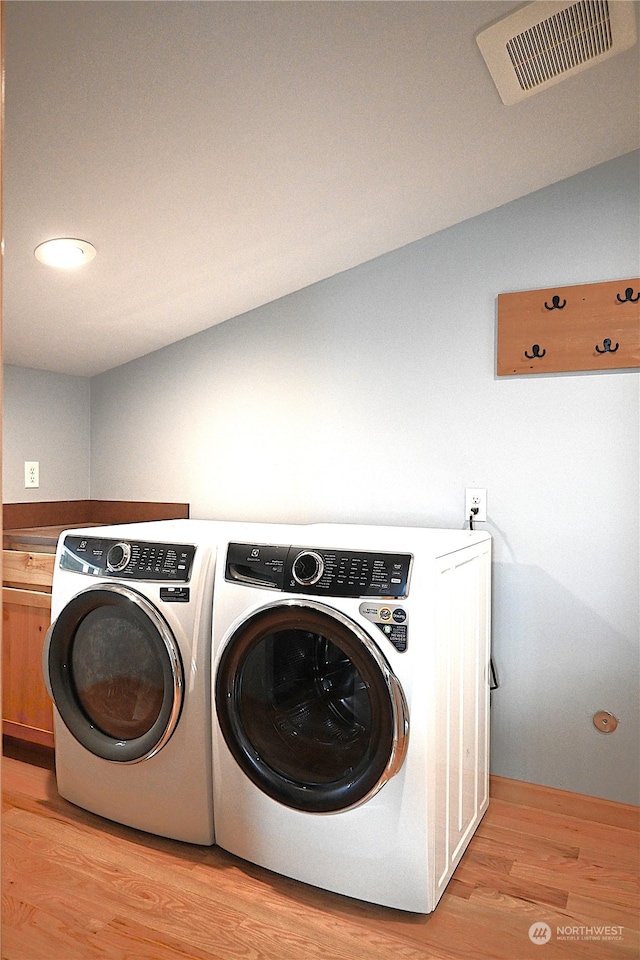 laundry room with light hardwood / wood-style flooring, cabinets, and washer and dryer