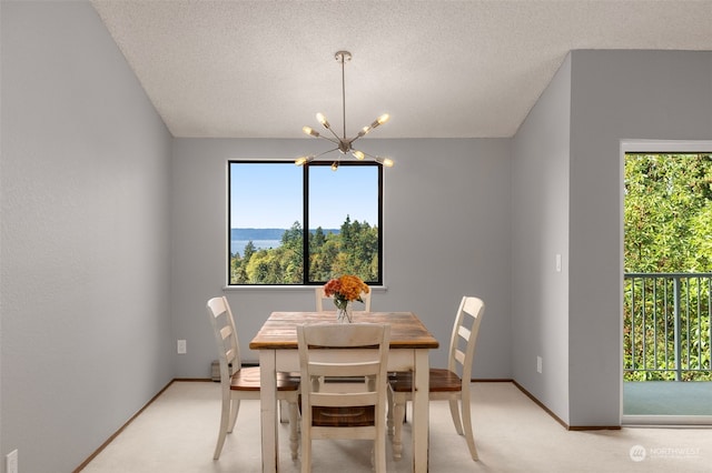 carpeted dining room featuring a notable chandelier and a textured ceiling