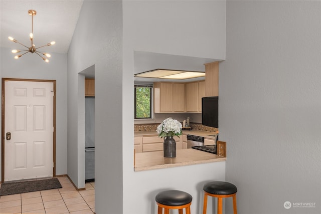 kitchen featuring stainless steel appliances, a notable chandelier, light tile patterned floors, light brown cabinetry, and high vaulted ceiling