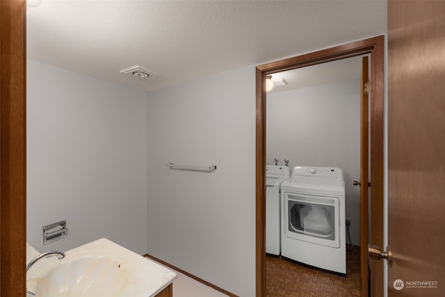 bathroom featuring parquet flooring, a textured ceiling, and washing machine and dryer